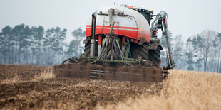 Eine Traktor verteilt Gülle auf einem Feld