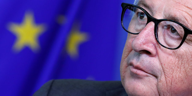 EU-Kommissionschef Jean-Claude Junckers Gesicht vor einer EU-Fahne