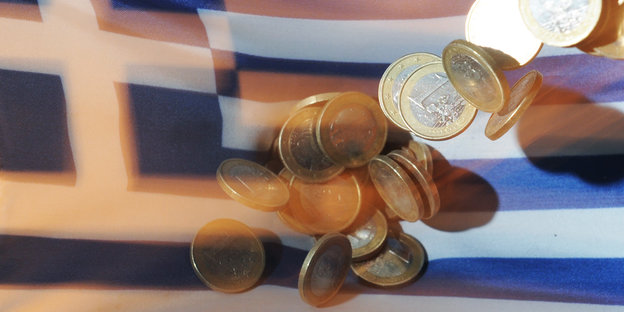 Euromünzen fallen auf eine Griechenlandflagge