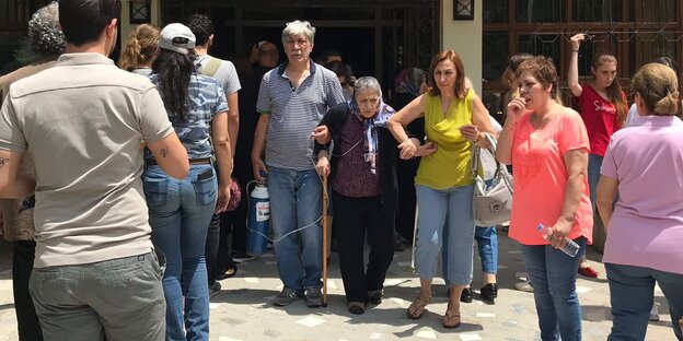 Ein Mann und eine Frau helfen einer alten Frau aus dem Wahllokal Ein Mann und eine Frau helfen einer alten Frau aus dem Wahllokal