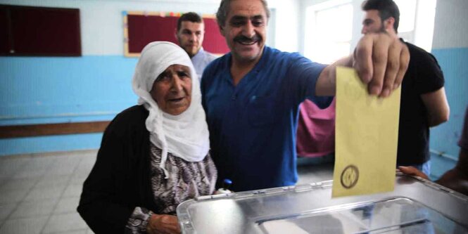 Die 107-jährige Kumri Ağdemir steht an der Wahlurne, ein Mann hilft ihr bei der Stimmabgabe