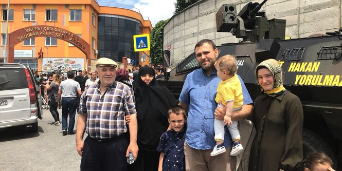 Eine türkische Familuie steht vor einem gepanzerten Fahrzeug vor einer zum Wahllokal umfunktionierten Schule in Istanbul