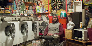 Ein Mann sitzt neben mehreren Waschmaschinen