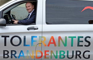 Brandenburgs Ministerpräsident Woidke sitzt in einem Auto mit der Aufschrift Tolerantes Brandenburg