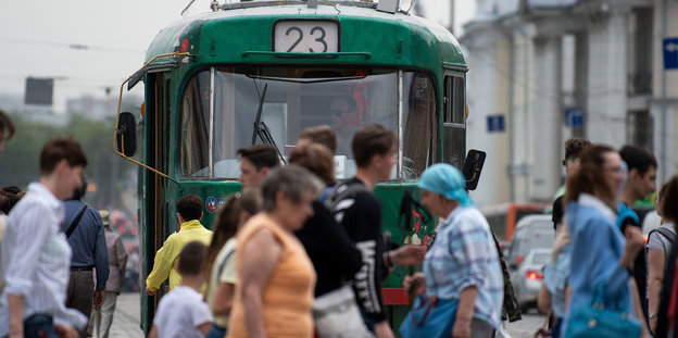 In Jekaterinburg gehen Passanten vor einer Straßenbahn entlang