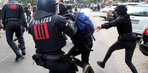 Ein Polizist schlägt mit seinem Knüppel einen G20-Gegner.