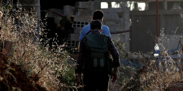Kämpfer der Freien Syrischen Armee vor einem zerstörten Gebäude in Daraa