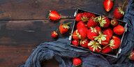 Erdbeeren in einer Schale, auf einem Tuch, auf einer Holzfläche