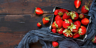 Erdbeeren in einer Schale, auf einem Tuch, auf einer Holzfläche