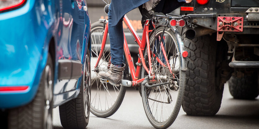 Ein Radfahrer, eingeklemmt zwischen zwei Autos