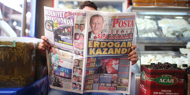 Ein Mann liest in einem Kiosk eine Tageszeitung
