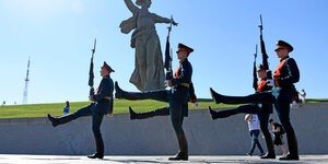 Soldaten marschieren an eunem Denkmal vorbei