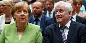Bundeskanzlerin Angela Merkel und Innenminister Horst Seehofer sitzen bei einer Veranstaltung