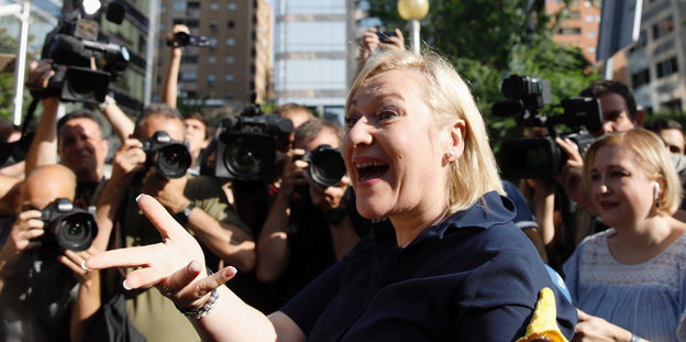 Ines Madrigal gestikuliert, im Hintergrund Journalisten mit Kameras