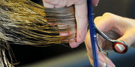 Eine Schere setzt an Haaren an, um diese abzuschneiden