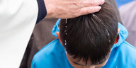 Ein Priester gießt einem Jungen Wasser über den Kopf