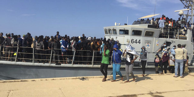 Schwarzafrikaner auf einem überfüllten Schiff; ein paar sind bereits an Land gegangen