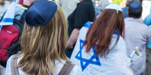 Zwei Kippa tragende Mädchen von hinten, eine davon hat sich in eine Israel-Fahne eingehüllt