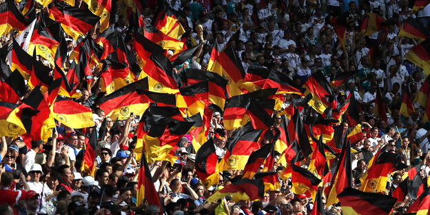 Fans von Deutschland schwenken vor Spielbeginn Deutschlandfahnen auf der Tribüne.
