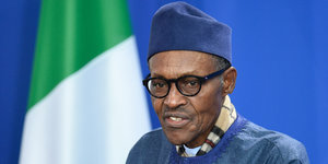 Der Präsident Nigerias, Muhammadu Buhari, steht vor der nigerianischen Flagge