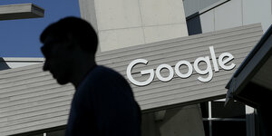 Die Silouette eines Menschen vor einem Gebäude, auf dem das Logo von Google zu sehen ist