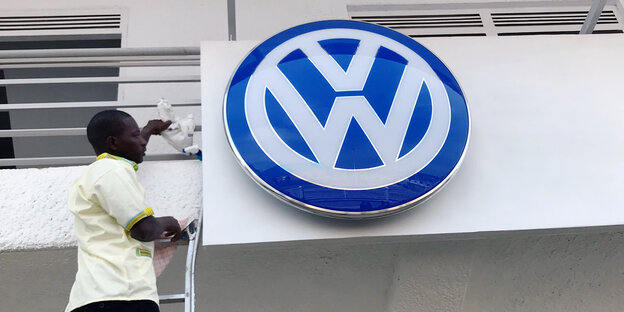 Ein Mann putzt das VW-Logo über dem nagelneuen Werk in Ruanda
