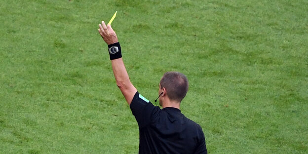 Ein Schiedsrichter zeigt die gelbe Karte
