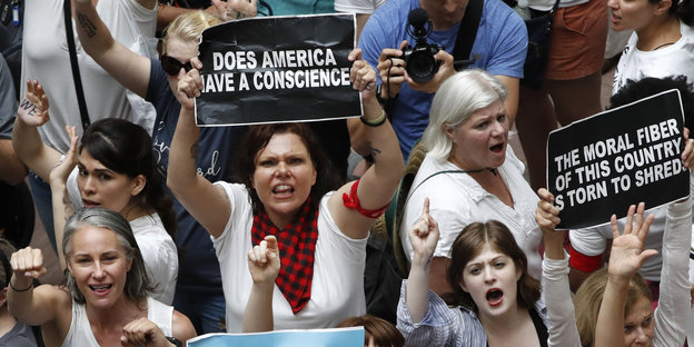 Protest gegen die US-Einwanderungspolitik - Frauen sitzen auf dem Boden, eine hält ein Schild hoch mit der Aufschrift "Does America have a conscience" - "Hat Amerika ein Gewissen"