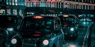 Ein Black Cab im nächtlichen, von Leuchtreklamen erhellten London