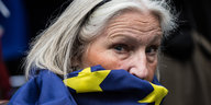 Nahaufnahme einer Frau, sie trägt eine Europaflagge als Schal, die ihr Gesicht halb verhüllt