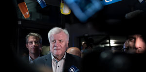 Unionsstreit - CSU-Chef Seehofer vor dunklem Hintergrund, Mikrophone um ihn rum