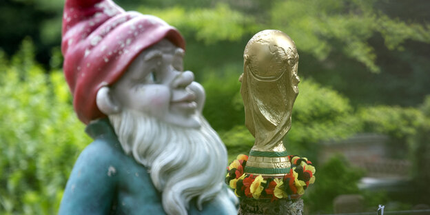 Ein nachgebildeter FIFA-WM-Pokal mit einer Girlande in den deutschen Nationalfarben und ein großer Gartenzwerg stehen im Vorgarten eines Hauses