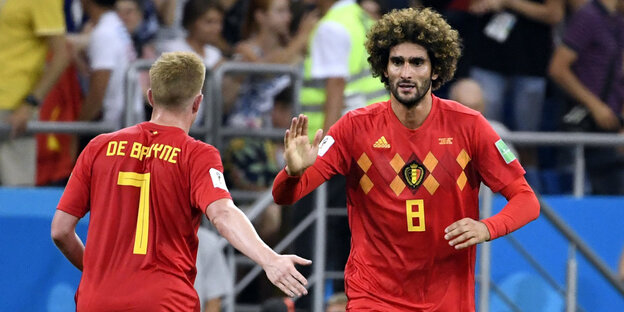 Belgien siegt gegen Japan im Achtelfinale - zwei Spieler in roten Trikots, darauf ein eckiges gelbes Muster