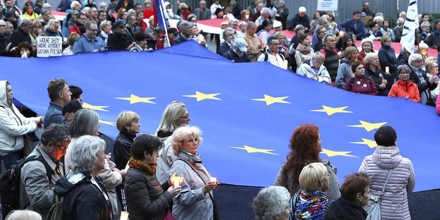 Rund um eine große EU-Flagge stehen Demonstrantinnen und Demonstranten mit Kerzen