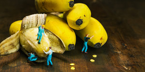 Kleine Spielfiguren klettern auf Bananen herum