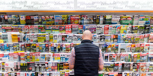 Ein Mann steht vor einem Zeitschriftenregal mit großer Auswahl