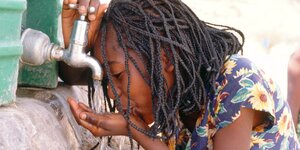 Namibisches Mädchen trinkt aus Wasserhahn