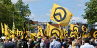 Personen stehen mit Fahnen der Identitären Bewegung auf der Straße