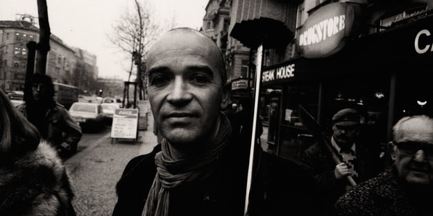 Schwarz-Weiß-Bild von Conrad Schnitzler auf einer Straße, er lächelt leicht