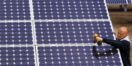 Ein Mann montiert Solarmodule auf einer Photovoltaikanlage