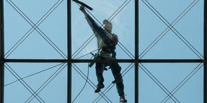 Ein Mann putzt ein gläsernes Dach