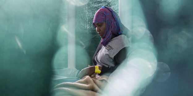 Eine geflüchtete Frau sitzt in einem Zelt an Bord eines Rettungsbootes