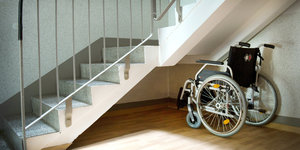 Ein Rollstuhl steht unter einem Treppenaufgang