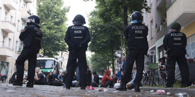 Eine Reihe Polizisten steht vor auf der Straße sitzenden Menschen