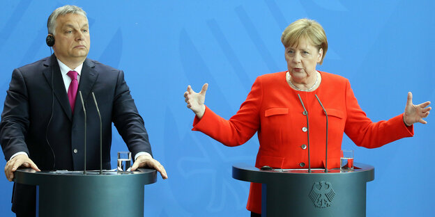 Viktor Orban und Angela Merkel stehen an Pulten