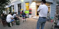 Menschen schauen Fußball vor einem Kiosk