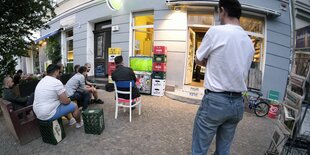 Menschen schauen Fußball vor einem Kiosk