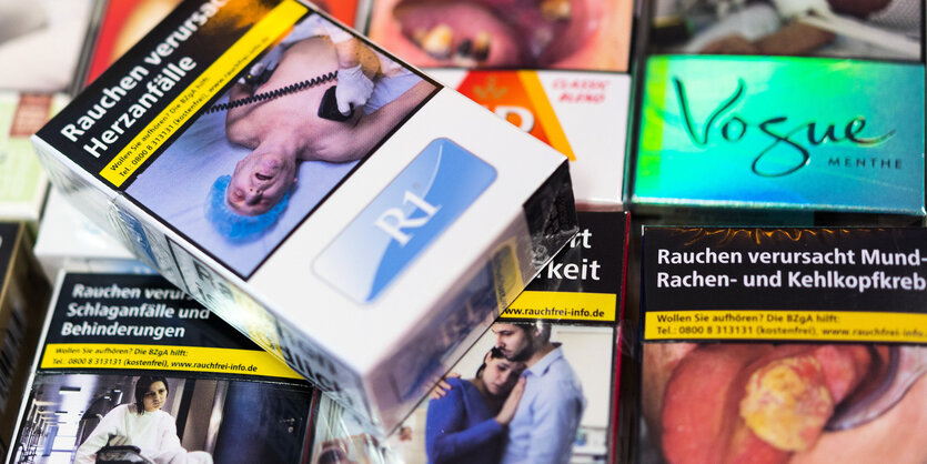 Zigarettenschachteln mit Schockbildern liegen auf einem Tresen in einem Kiosk