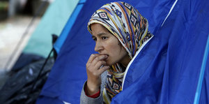 Eine Frau guckt nachdenklich aus einem Zelt