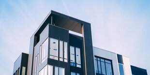 Ein modernes Wohnhaus mit viel Glas vor einem blauen, leicht bewölkten Himmel